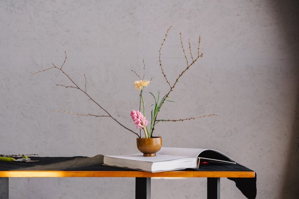 photo A serene still life featuring a wooden vase with flowers on an open book.